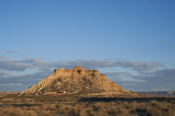 Distant view of shepherds hut under the white mountain in the Bardenas Reales in Navarra. Semi-desert landscape of northern Spain.