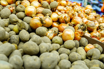 Potatoes and onions are in a pile in the store for sale