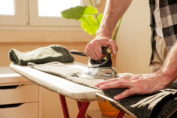 Obraz premium Handsome single male ironing his clothes in the house