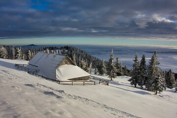 Landscape shot of a shepherd cottage surrounded by fluffy white snow on Velika Planina in Slovenia