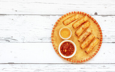 Traditional Vietnamese juicy and crispy fried meat rolls with sesame sauce on a white wooden board