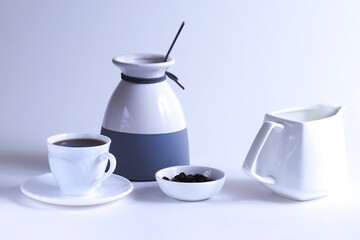 white cup with brewed coffee and coffee beans in a white plate. Shallow depth of field