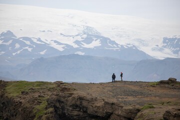 Hikers on the edge of the hill in Iceland watching the glacier