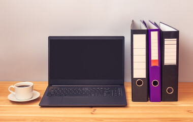 Laptop, folders and coffee cup on office desk