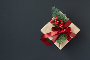 Banner with craft gift box with red ribbon and thuja sprig on a dark background. Top view,...