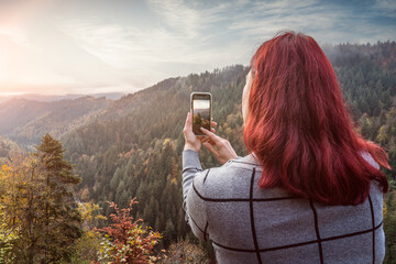 Frau macht ein Landschaftsfoto mit dem Handy