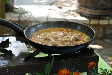 Corn and meat meal cooking in a pan on an outdoor stove in the daylight