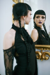 Gothic girl looking at herself in a mirror, judging her reflection, dark laced dress