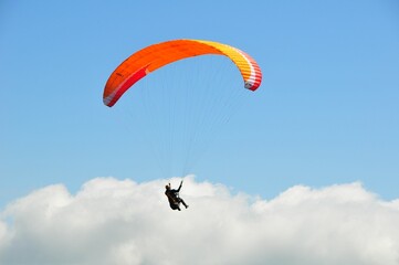 Closeup of a paraglider flying in the air against a bright blue sky