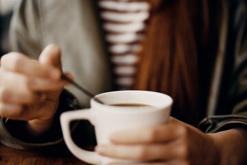 Woman in cafe stirring sugar in white coffee mug, autumn vibe and warm content for social media, blogger