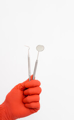Denistry instruments in gloved hands. Dental tools on isolated background.