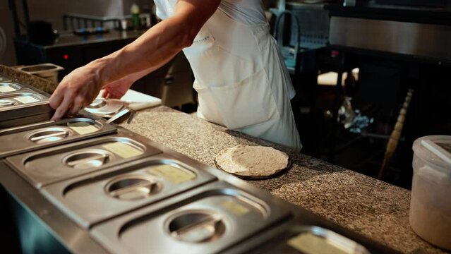 Male chef adds garlic sauce to the tortilla in restaurant kitchen