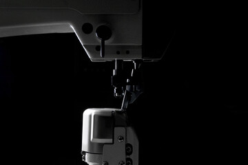 industrial sewing machine with a needle in work on black background.