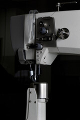 industrial sewing machine with a needle in work on black background.