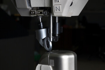 industrial sewing machine with a needle in work on black background.