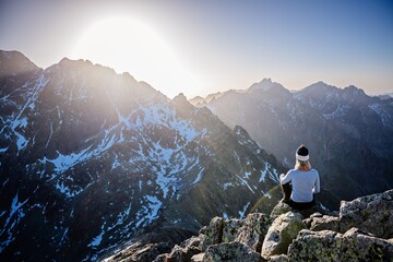 Beautiful blonde woman enjoys reaching the summit in the Slovak Tatras and looks at the Gerlach...