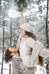 Fototapeta na wymiar Romantic snow love story.Young couple guy girl lying,playing in snowy winter forest with trees.Walking, having fun, laughing in stylish warm clothes, fur coat,woole jacket,shawl.Date,vacation weekend