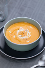 Creamy pumpkin soup garnished with  cooking sauce served in turquoise dish with slice of bread in rustic mood. Seasonal warm food. Autumn Appetiser 