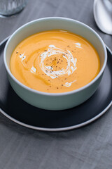 Creamy pumpkin soup garnished with  cooking sauce served in turquoise dish with slice of bread in rustic mood. Seasonal warm food. Autumn Appetiser 