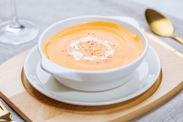 Creamy pumpkin soup garnished with  cooking sauce served in turquoise dish with slice of bread in rustic mood. Seasonal warm food. Autumn Appetiser 