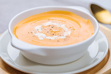 Creamy pumpkin soup garnished with  cooking sauce served in turquoise dish with slice of bread in rustic mood. Seasonal warm food. Autumn Appetiser 