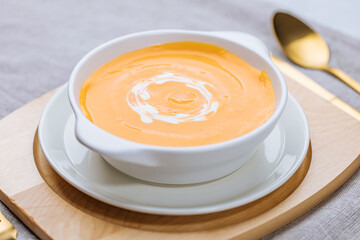 Creamy pumpkin soup garnished with  cooking sauce served in turquoise dish with slice of bread in rustic mood. Seasonal warm food. Autumn Appetiser 