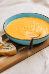Creamy pumpkin soup garnished with  cooking sauce served in turquoise dish with slice of bread in rustic mood. Seasonal warm food. Autumn Appetiser 