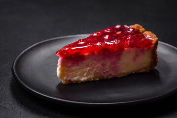 Homemade tasty cheesecake with jelly and raspberry berries on a black plate