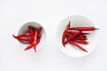 Red hot capsicum in a white bowl. Spicy red pepper in a plate close-up on a white background.