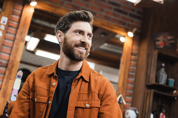 Fototapeta premium happy brunette man with beard looking away in beauty salon.