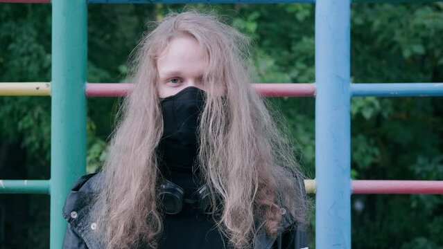 Portrait of young blond man wearing black mask close-up outdoor