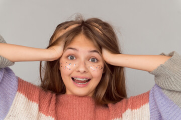 Emotional portrait of young happy girl with freckles open mouth surprised face isolated on gray