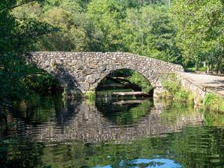 Fototapeta na wymiar Puente de piedra cruzando el río con reflejos
