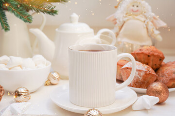   Winter, Christmas, New Year decoration composition, concept, background. White Mug, cup of hot tea, coffee, meringue, knitted plaid. Christmas lights. Christmas mood morning. Xmas greeting card.
