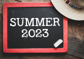 Summer 2023 written on a chalkboard in the background of sunny weather in a hotel resort.