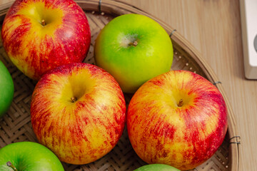 red and green apples isolated in wicker basket with wooden background
