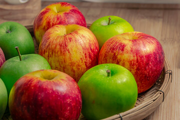 red and green apples isolated in wicker basket with wooden background