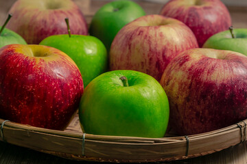 red and green apples isolated in wicker basket with wooden background