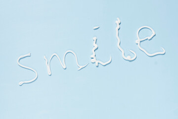 the word smile written in white paint on a blue background, with an airplane flying overhead above it and below