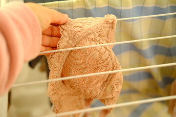 female hands of middle-aged woman close-up hang wet washed linen, bra on wire dryer, gentle hand washing of lacy underwear, housewife at homework, selective focus at shallow depth of field - obrazy, fototapety, plakaty