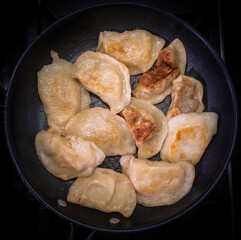 Fried dumplings with cabbage, cheese and potatoes in a pan with lard. The skin is browned and browned.