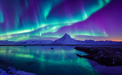 Aurora borealis landscape in the far north and the polar night. Beautiful green gleams of the atmospheric luminous phenomenon characterized by extremely colored veils. Reflection in the water.