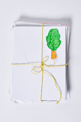 a green leaf tied to a white piece of paper with a yellow ribbon around it, on a white surface