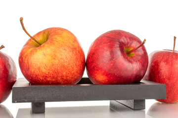 Several red ripe apples on a wooden plate, macro, isolated on white background.