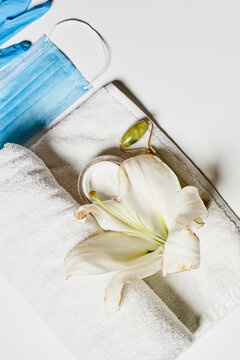 a white flower on a towel with a blue face mask in the photo has been taken from above it and is not visible