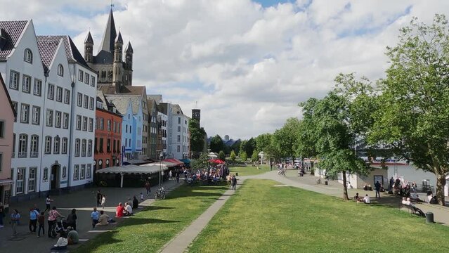 People relaxint in park at colorful old buildings and church Gross St. Martin in the old town of Cologne, Germany, aerial shot slow motion