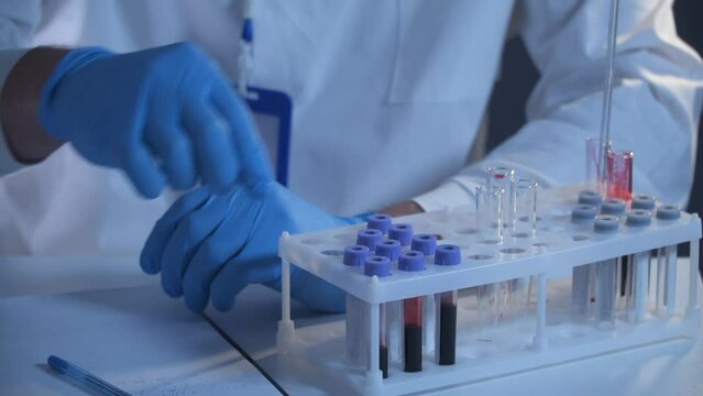 Health care worker with blood test tubes in clinical laboratory. Medical examiners hand holding blood sample for analysis in clinical research laboratory. Disease prevention starting in science center