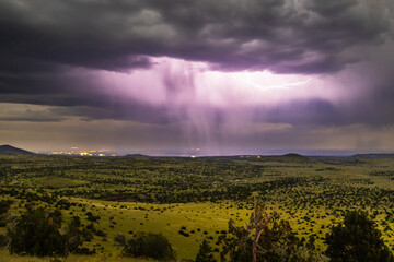 Lighting bolt under a cloud as rain comes down over open wilderness in Northern Arizona.