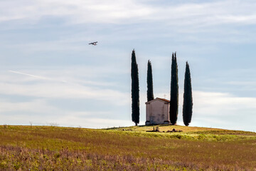 A small touring plane flies over the ancient Church of San Pierino in Camugliano, Ponsacco, Pisa, Italy