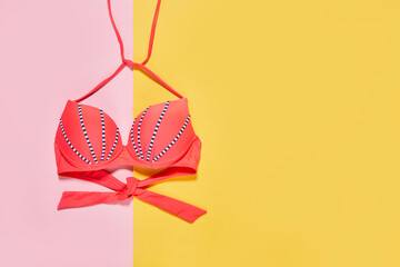 a bikini top on a yellow and pink background with copy - space in the bottom right handwritten text...